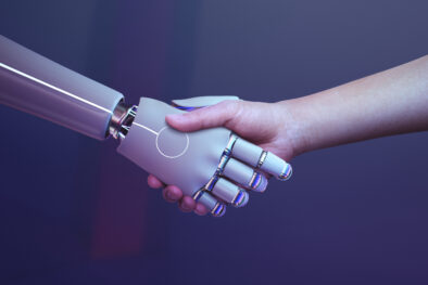 A robot and a human hand engage in a handshake, symbolizing the intersection of technology and humanity. The robot's hand is made of shiny metal with blue illuminated joints, while the human hand appears natural with visible skin texture. The background is in shades of purple, adding a futuristic feel to the scene.