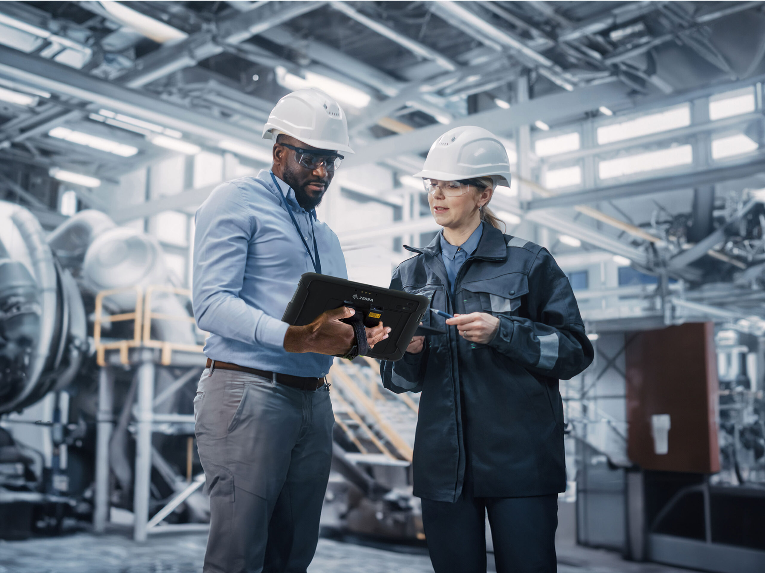 Two manufacturing engineers using a Zebra rugged tablet to manage factory operations and production workflows