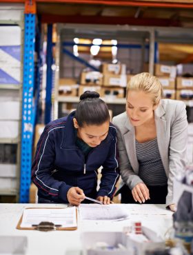 Cropped shot of a young woman and her boss doing stock take in a warehouse. Cropped shot of a young woman and her boss doing stock take in a warehouse.